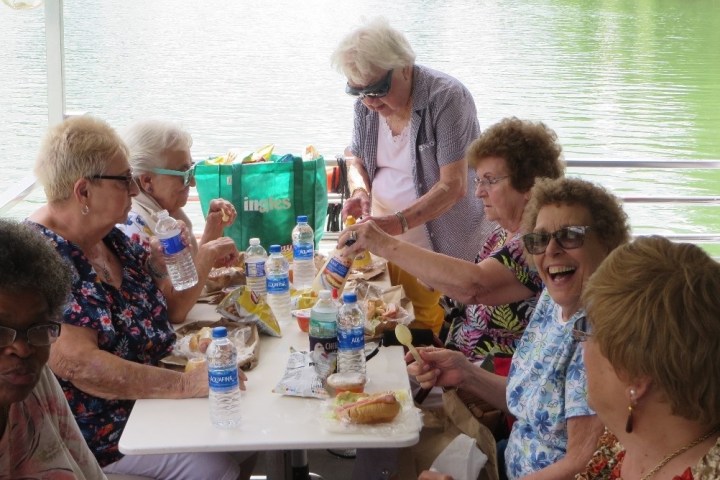 a group of people sitting at a table with food and water